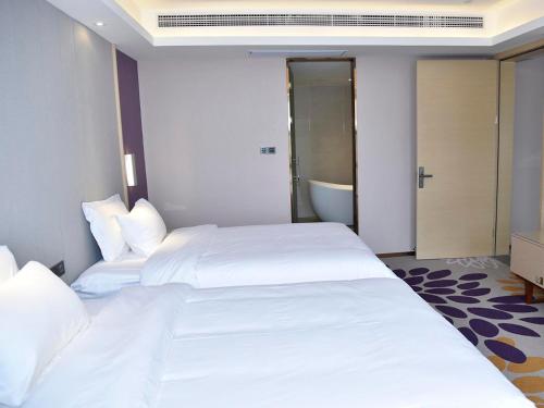 a hotel room with two beds and a bathroom at Lavande Hotel Fuzhou Wanda Plaza High-speed Railway Station in Fuzhou