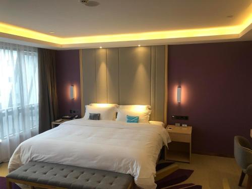 a bedroom with a large white bed and a chair at Lavande Hotel Zhoushan Putuo in Zhoushan