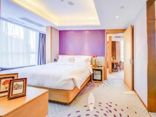 a bedroom with a large bed and a purple wall at Lavande Hotel (Shenyang Olympic Center Wanda Branch) in Shenyang