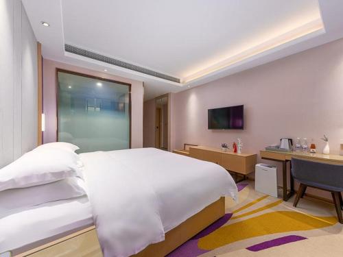 a bedroom with a large white bed and a desk at Lavande Hotel (Guangzhou North Railway Station Branch) in Huadu