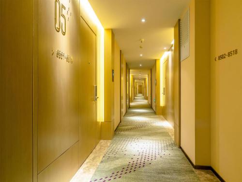 a corridor with yellow walls and a long hallway with a hallway at Lavande Hotel Qiqihar Supervisory Office in Qiqihar