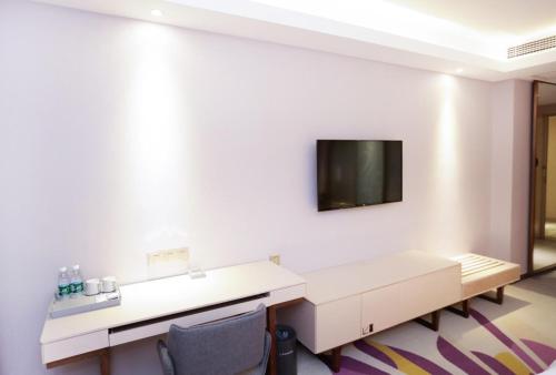 a room with a desk and a tv on a wall at Lavande Hotel (Jingdezhen Taoxichuan Creative Square Branch) in Jingdezhen