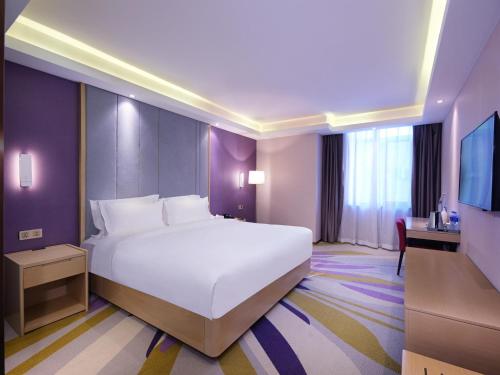 a bedroom with a large white bed and a tv at Lavande Hotel (Harbin Ice and Snow World University of Commerce Branch) in Harbin