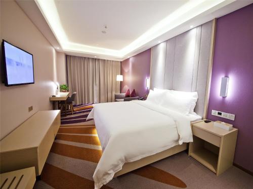 a bedroom with a large white bed and purple walls at Lavande Hotel (Changsha Railway Station Chaoyang Metro Station Branch) in Changsha