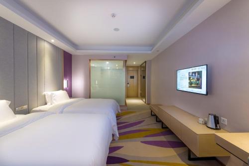 a hotel room with two beds and a tv on the wall at Lavande Hotel (Harbin Ice and Snow World University of Commerce Branch) in Harbin