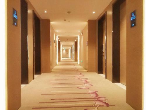 a hallway in a hotel with a long corridor with footprints on the floor at Lavande Hotel Jinan Second Ring East Road Quanfu Overpass Branch in Jinan