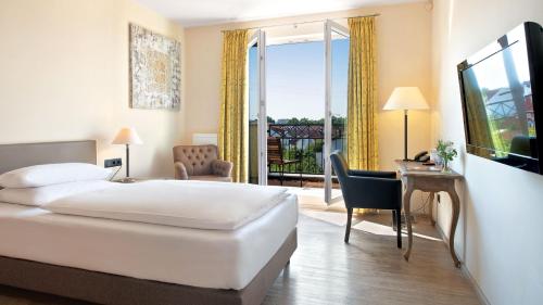 a hotel room with a bed and a desk and a balcony at Hotel Villa Toskana in Leimen