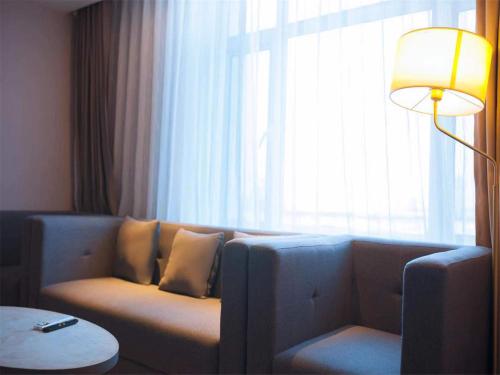 a living room with a couch in front of a window at Lavande Hotel Qiqihar Supervisory Office in Qiqihar