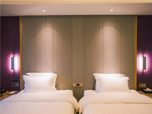 two beds with white pillows in a room at Lavande Hotel (Nanchang West Railway Station Square Branch) in Nanchang