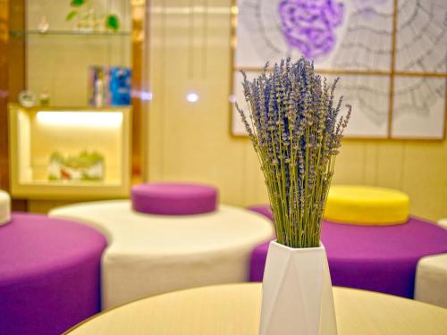 a white vase with purple flowers sitting on a table at Lavande Hotel Fuzhou Wanda Plaza High-speed Railway Station in Fuzhou