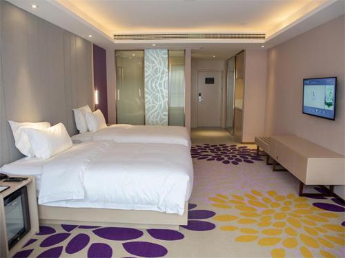 a bedroom with a large bed and a flat screen tv at Lavande Hotel Enshi Cultural Center in Enshi