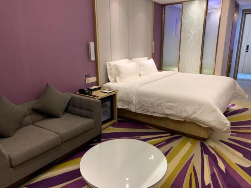 a bedroom with a bed and a couch and a table at Lavande Hotel (Nanchang West Railway Station Square Branch) in Nanchang