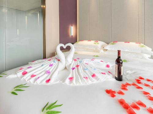two swans making a heart on a bed with a bottle of wine at Lavande Hotel Changsha Xingsha Center in Xingsha