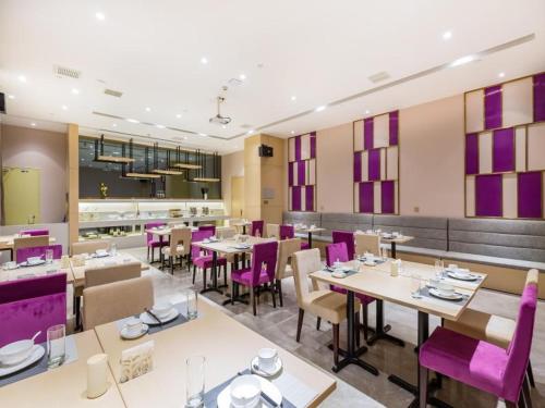 a dining room with tables and purple chairs at Lavande Hotel Langfang City Government in Langfang