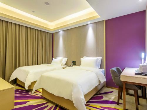 two beds in a hotel room with purple walls at Lavande Hotel Qiqihar Supervisory Office in Qiqihar