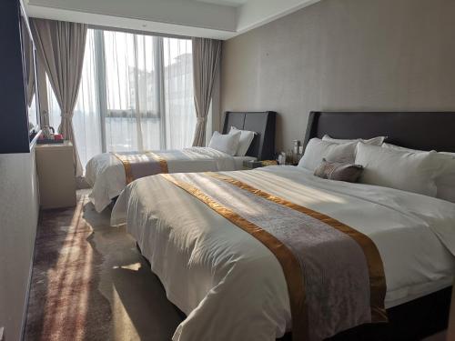 two beds in a hotel room with large windows at Lavande Hotel Shijiazhuang Zhonghua North Street Zhongchu Plaza Branch in Shijiazhuang