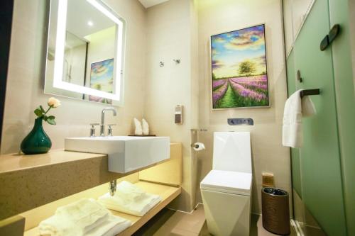une salle de bain avec un lavabo, des toilettes et un miroir dans l'établissement Lavande Hotel Xuzhou East High-speed Rail Station Jinshanqiao Development Zone Branch, à Xuzhou