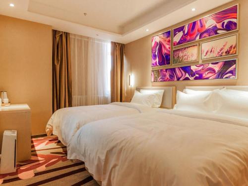 a bedroom with two beds and a painting on the wall at Lavande Hotel Zhangjiakou Victoria Plaza in Zhangjiakou