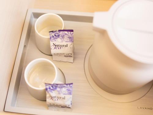 a tray with two cups and a bowl on a table at Lavande Hotel (Zibo Beijing Road Huaqiao Building Branch) in Zibo