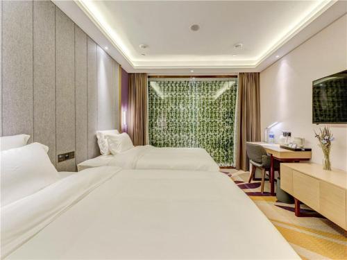 a hotel room with two beds and a desk at Lavande Hotel Tangshan Convention and Exhibition Yuanyang City in Tangshan