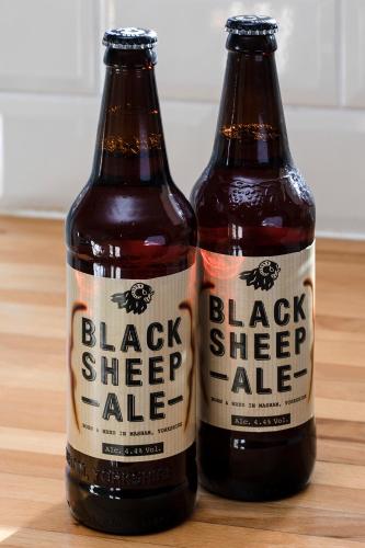 two bottles of beer sitting on a wooden table at Cosy Cottages in Masham in Masham