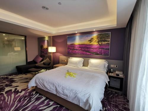a bedroom with a large bed with a painting on the wall at Lavande Hotel (Changchun Yiqi Branch) in Changchun