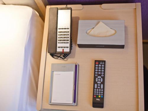 a bedside table with a remote control and other electronic devices at Lavande Hotel (Changsha Railway Station Branch) in Changsha