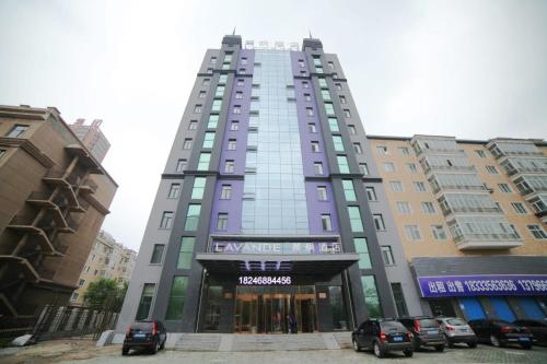 a tall building with cars parked in front of it at Lavande Hotel (Harbin Ice and Snow World University of Commerce Branch) in Harbin