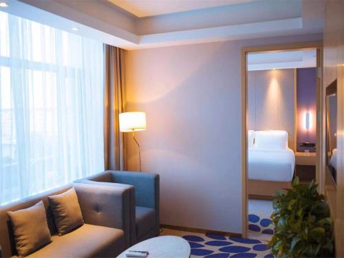 a hotel room with a couch and a bed at Lavande Hotel Qiqihar Supervisory Office in Qiqihar
