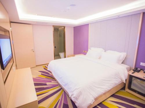 a bedroom with a white bed and a television at Lavande Hotel (Zibo Beijing Road Huaqiao Building Branch) in Zibo