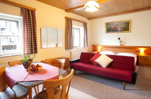 Una sala de estar con un sofá rojo y una mesa. en Palfnerhof Appartements, en Sankt Johann im Pongau