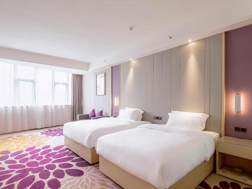 two beds in a hotel room with purple walls at Lavande Hotel Changsha Xingsha Center in Xingsha