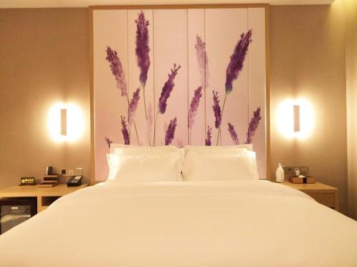 a bedroom with a large white bed with purple flowers on the wall at Lavande Hotel Jinan Second Ring East Road Quanfu Overpass Branch in Jinan