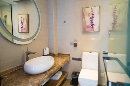 a bathroom with a sink and a mirror and a toilet at Lavande Hotel Xinyang Municipal Government Branch in Xinyang