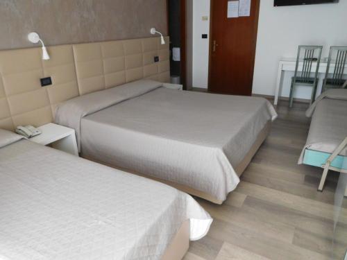 a bedroom with two beds and a wooden floor at Hotel Emperador in Lido di Jesolo
