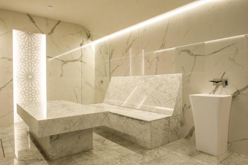 a white marble bathroom with a bench and a sink at Hotel Zalewski in Mrzeżyno