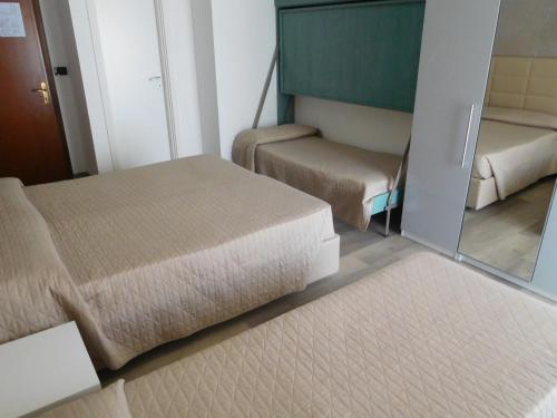 a small room with two beds and a mirror at Hotel Emperador in Lido di Jesolo