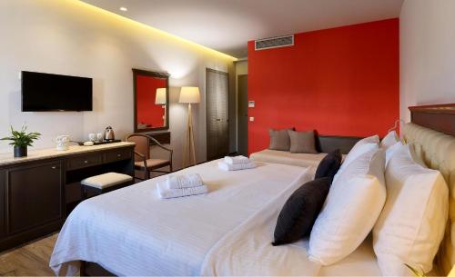 a hotel room with two beds and a red wall at Castello City Hotel in Heraklio Town