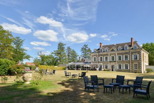 un groupe de chaises devant un grand bâtiment dans l'établissement Logis Domaine De Valaudran, à Salbris