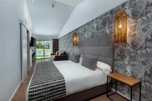 マスパロマスにあるKumara Serenoa By Lopesan Hotelsの白い大型ベッドと壁が備わるベッドルーム1室が備わります。