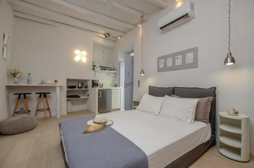 a white bedroom with a bed and a kitchen at Venetian Suites in Naxos Chora