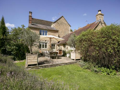 a house with a table and an umbrella in the yard at The Old Post Office in Cirencester
