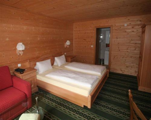 een slaapkamer met een bed en een rode bank bij Hotel Waldesruh in Göstling an der Ybbs