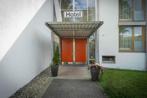 a hotel with a red door and two plants at Hotel Don Bosco in Aschau am Inn