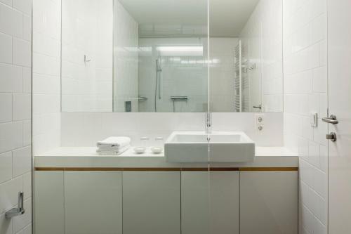 a white bathroom with a sink and a mirror at Aparthotel Chalet Wetzlgut in Bad Gastein
