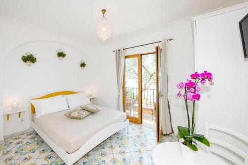 a white bedroom with a bed and a vase of flowers at La Borragine Rooms in Positano