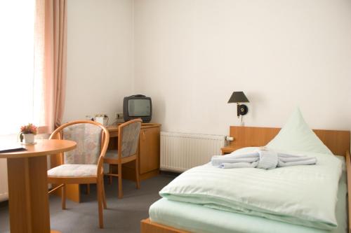 a bedroom with a bed and a table and a tv at Land-gut-Hotel Cafe Meier in Kurort Oybin