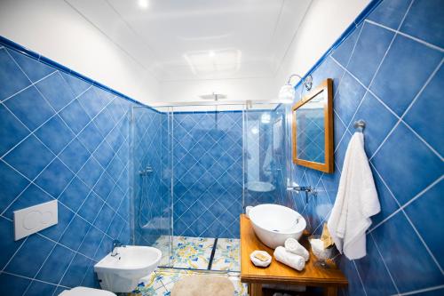 bagno piastrellato blu con servizi igienici e lavandino di La Borragine Rooms a Positano