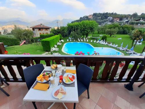 a table with food on a balcony with a pool at Park Hotel Val Di Monte ***S in Malcesine