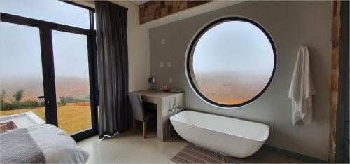 a bathroom with a tub and a large window at Highland Gate Golf Retreat in Dullstroom